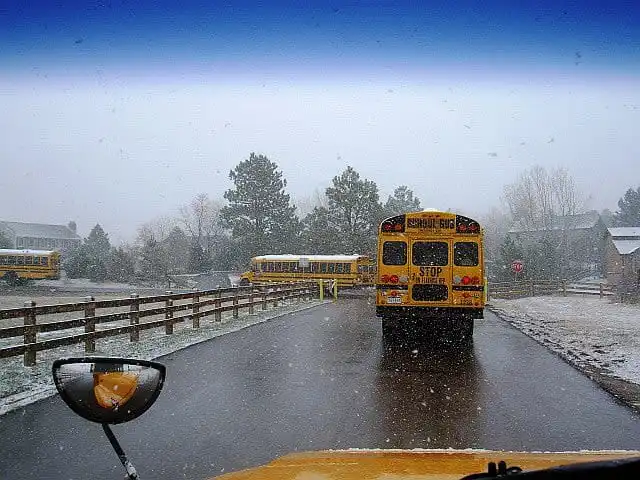 School bus driving on a snowy road during winter morning commute conditions
